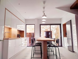 A modern kitchen with white cabinets, a wooden countertop, and a dining area with a table and chairs.