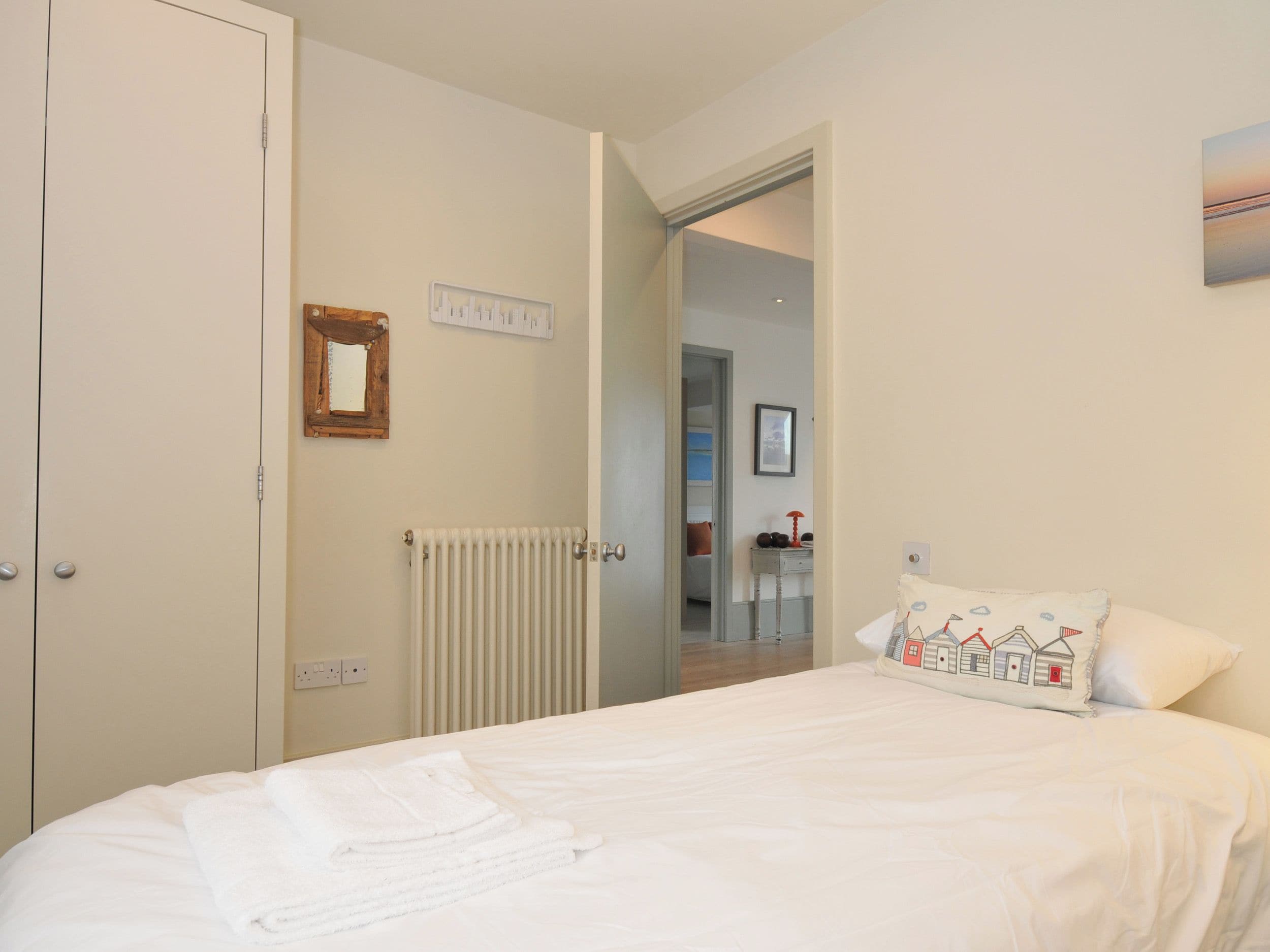 Une chambre à coucher avec un lit, un radiateur, une porte et un couloir menant à une autre pièce.
