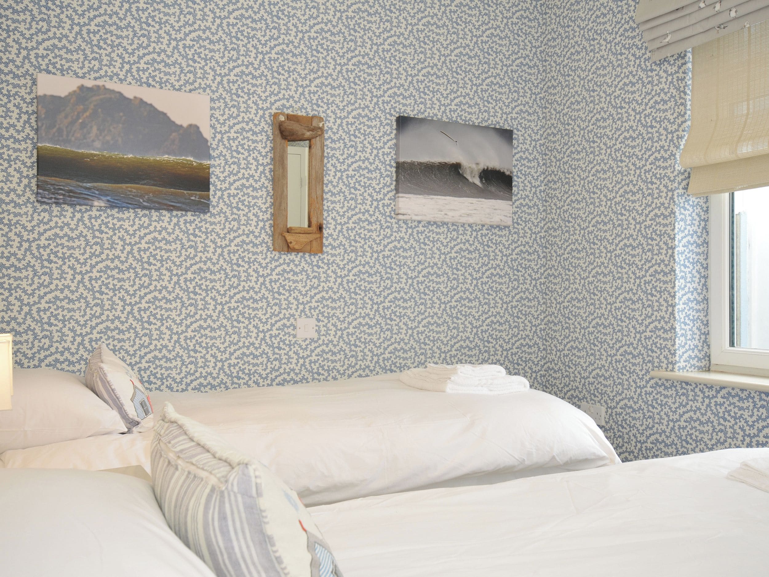Ein Schlafzimmer mit zwei Betten, einem Fenster und zwei Bildern an der Wand.