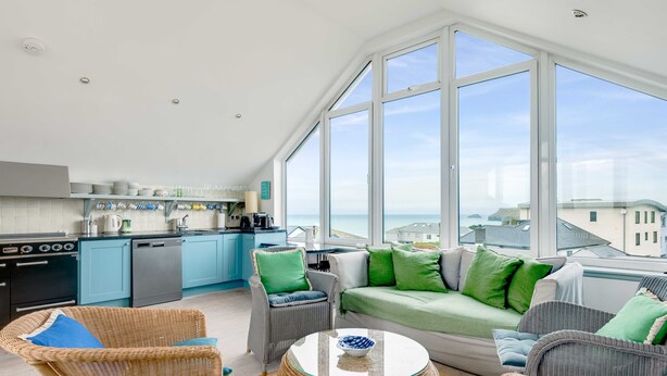 A bright kitchen with blue cabinets and a large window overlooking the sea. - The Point (Wadebridge)