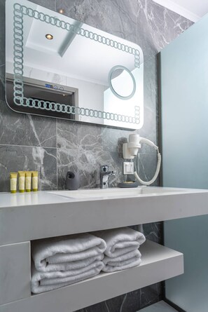 Enjoy a refreshing bathroom experience with a sleek vanity, large mirror, and hairdryer.