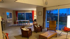 A spacious living room with a large sliding glass door leading to a balcony, a dining area with a table and chairs, and a cozy seating area with sofas and a coffee table. - Family home 2 steps from Arradon center, Gulf and beaches (Arradon)