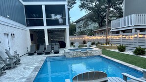Ein rechteckiger Pool mit Steinbord, umgeben von Liegestühlen und einer Sonnenterrasse.
