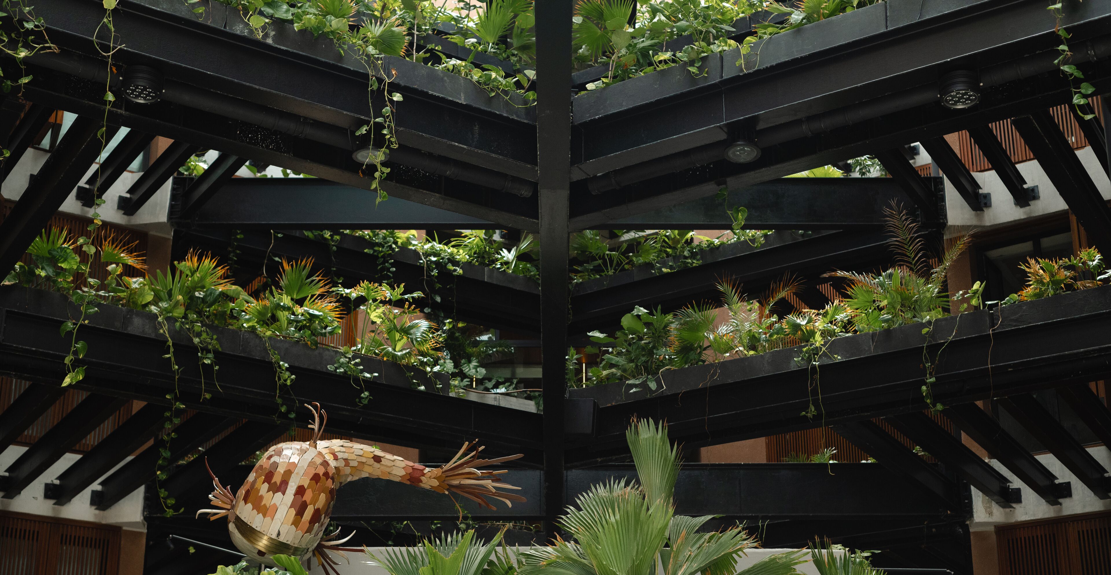 Un atrio de varios niveles con diversas plantas y una escultura decorativa.