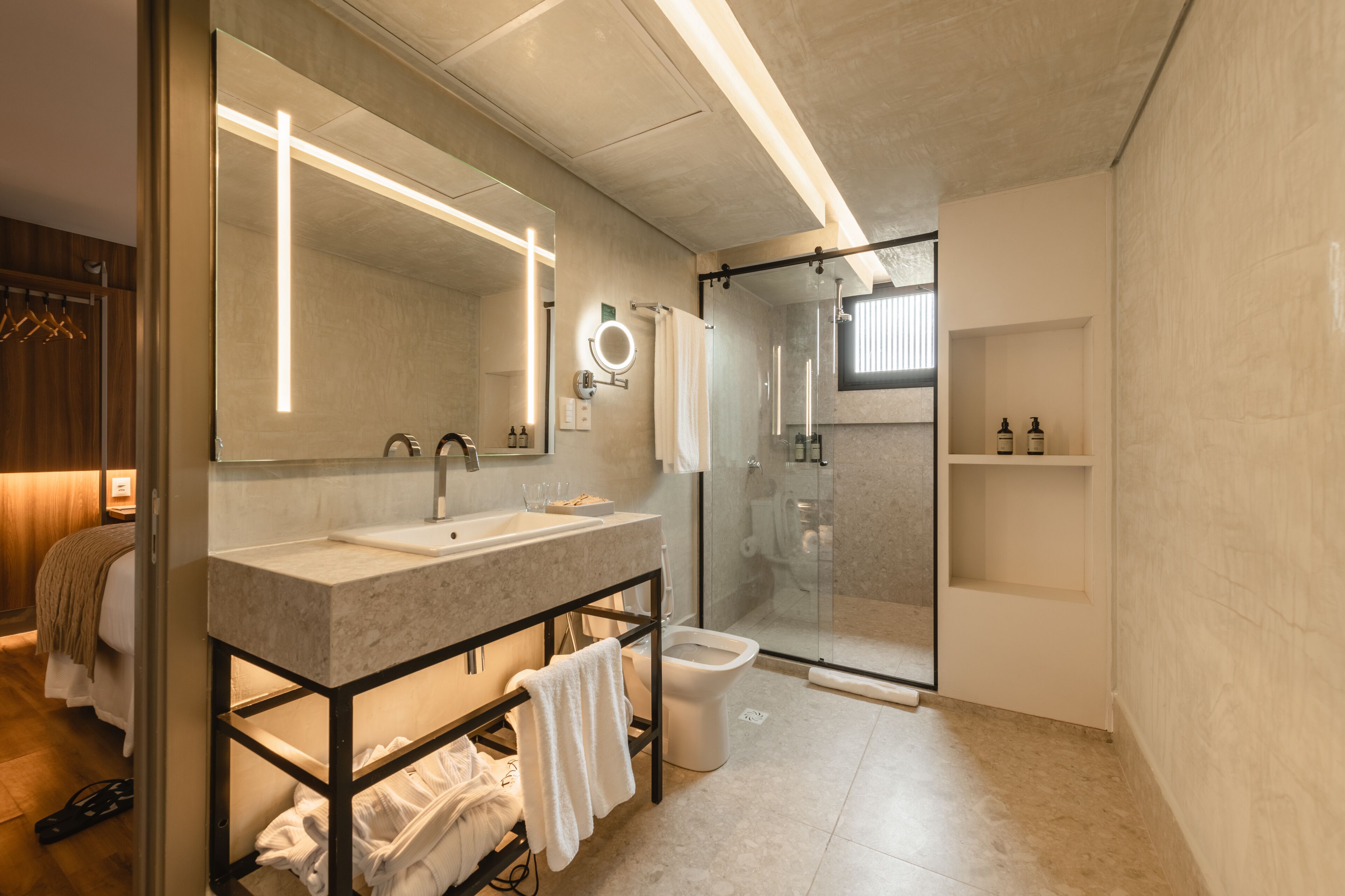 Un baño moderno con un espejo grande, lavamanos dobles, cabina de ducha de vidrio y un inodoro.