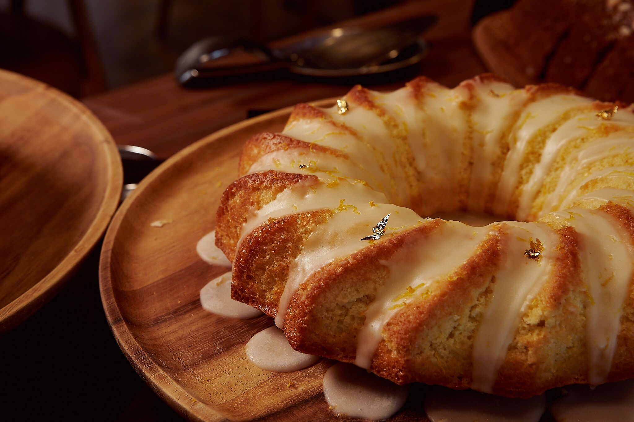 Un pastel Bundt con cobertura blanca sobre un plato de madera.