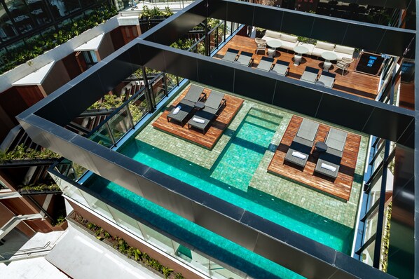 Et tagområde med swimmingpool, liggestole og træterrasse.
