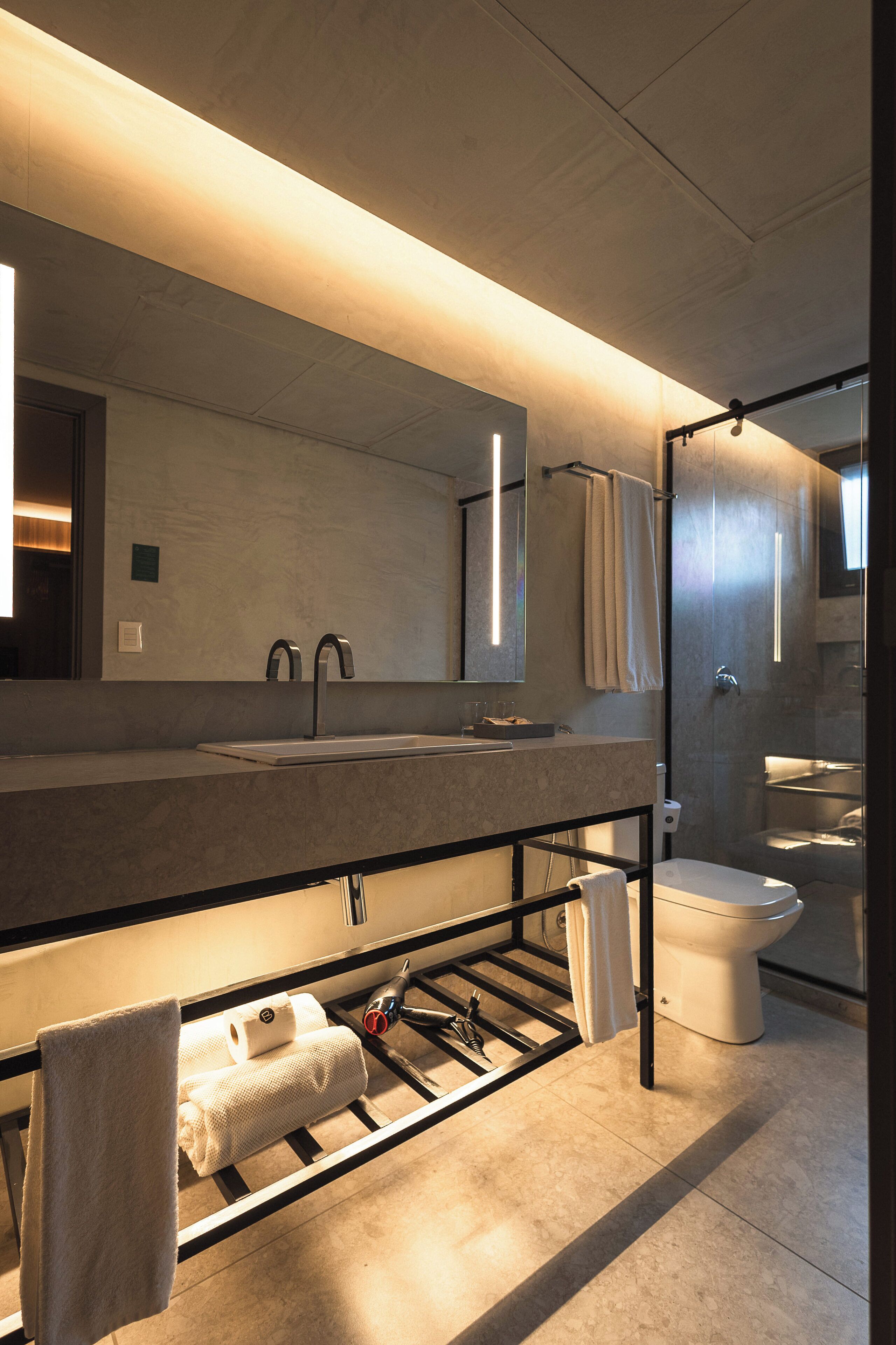 Un baño moderno con un espejo grande, un lavamanos y un inodoro.