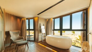 Una habitación moderna con un ventanal grande, una bañera, una silla y una mesita.