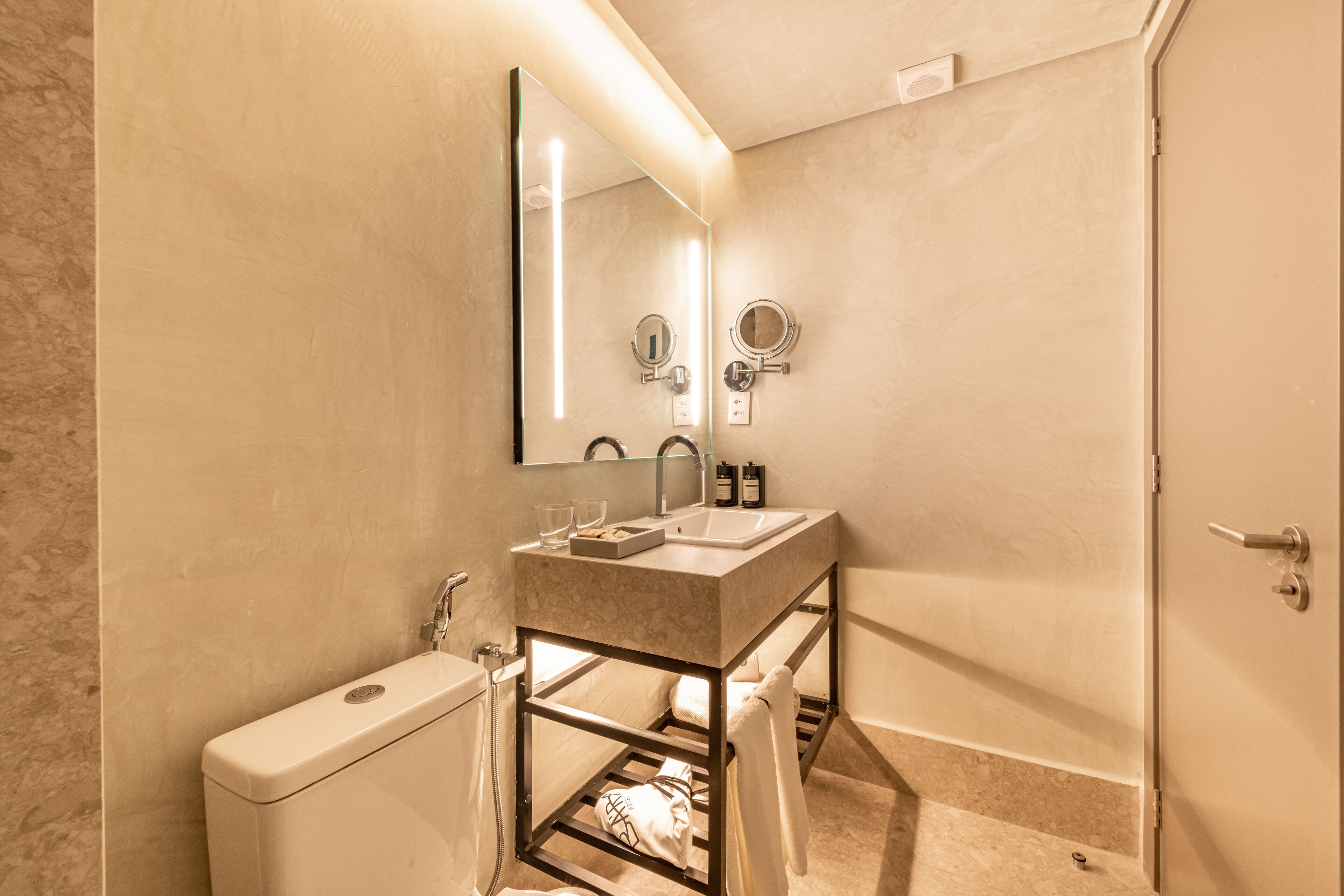 Un baño moderno con tocador de mármol, un espejo grande, inodoro y zona de ducha.