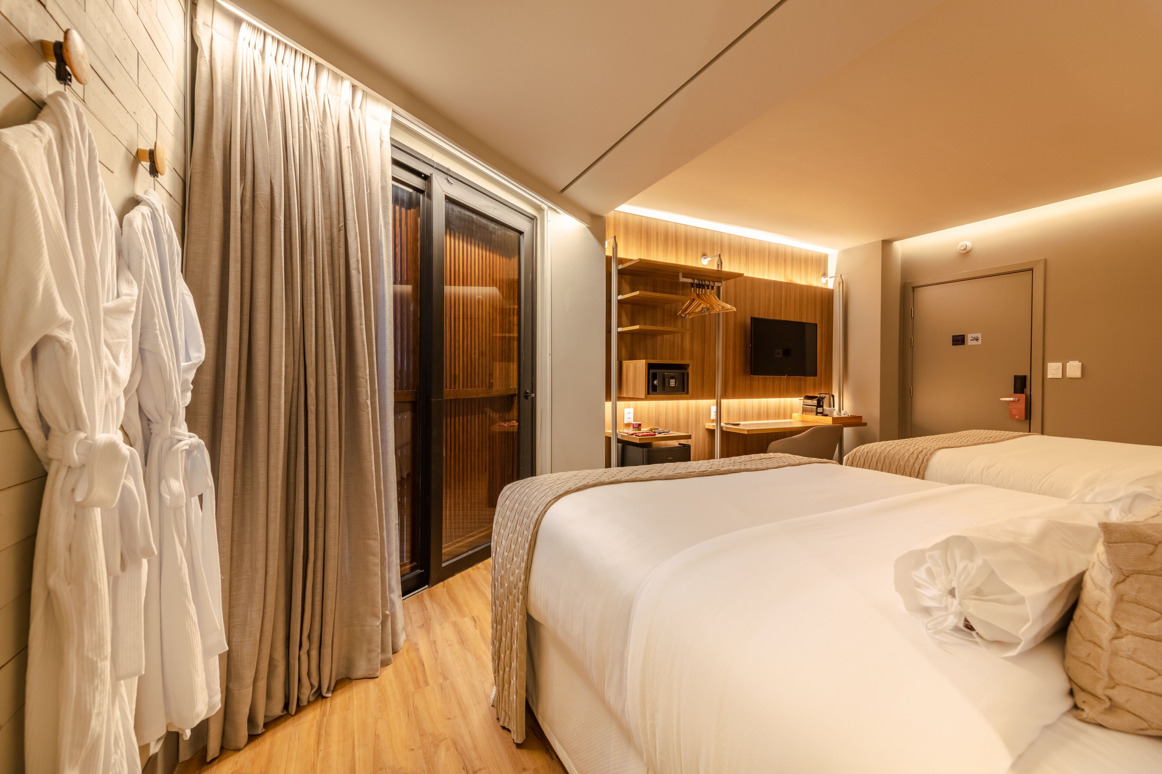 Une chambre d’hôtel avec un grand lit, un bureau, un miroir et une armoire.