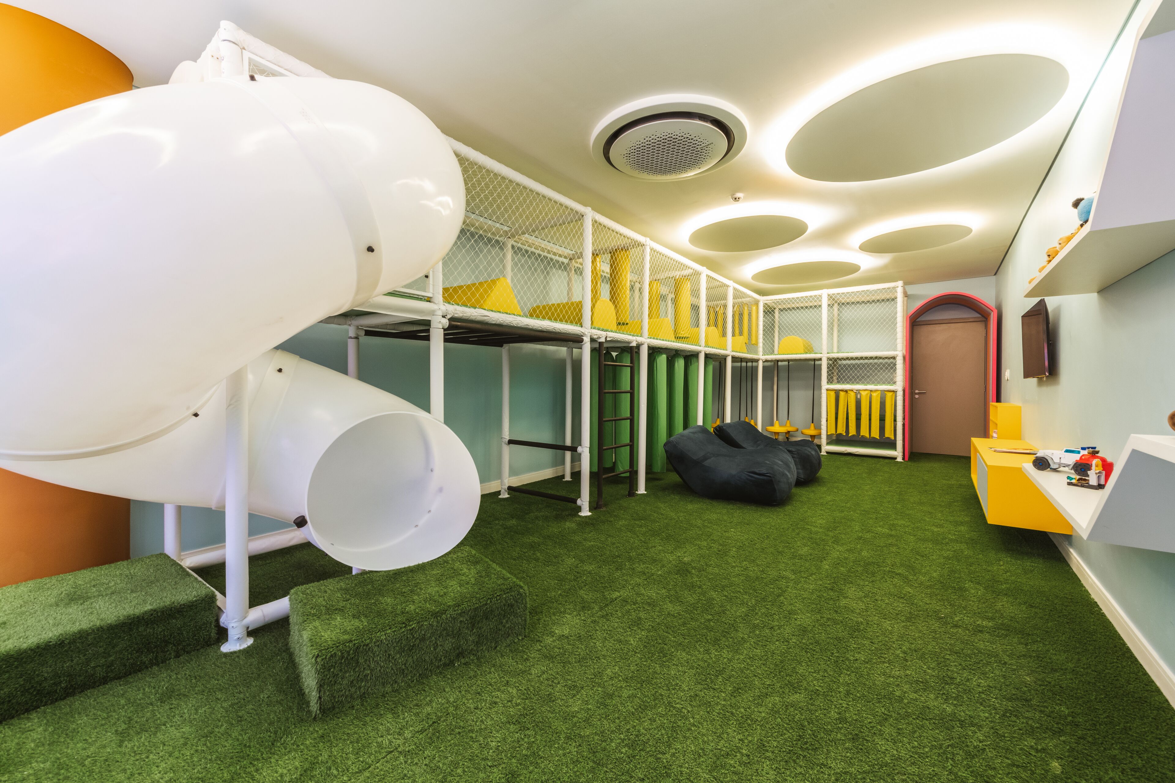 A children's play area with a slide, climbing steps, and soft play furniture.