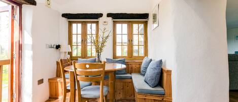 A cozy dining area with a wooden table, chairs, and a built-in bench with cushions.