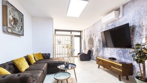A modern living room with a sectional sofa, a glass coffee table, a wooden sideboard, a flat-screen TV, and a potted plant. - LOFT with private jacuzzi, CENTRE VILLE PONTOISE (Pontoise)