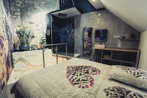 Un dormitorio con cama, ducha y baño pequeño.