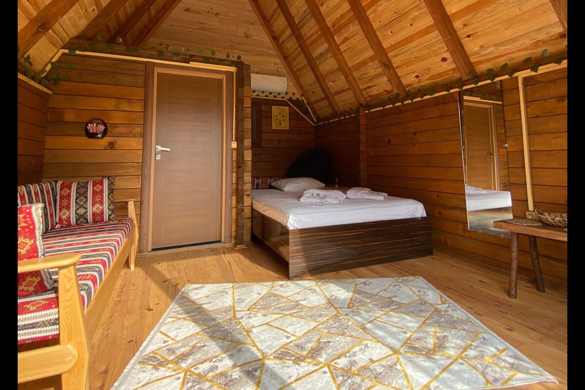 Una cabaña acogedora de madera con habitación en la buhardilla, un sofá y una alfombra estampada.