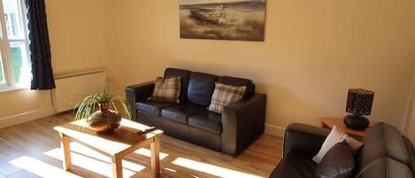 A living room with a sofa, a coffee table, and a painting on the wall.