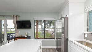 Una cocina moderna con una isla grande, muebles blancos y un refrigerador empotrado.
