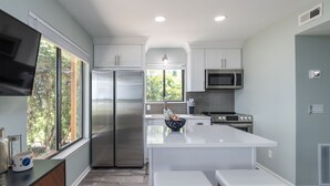 Una cocina moderna con una isla grande, electrodomésticos de acero inoxidable y vistas al exterior.