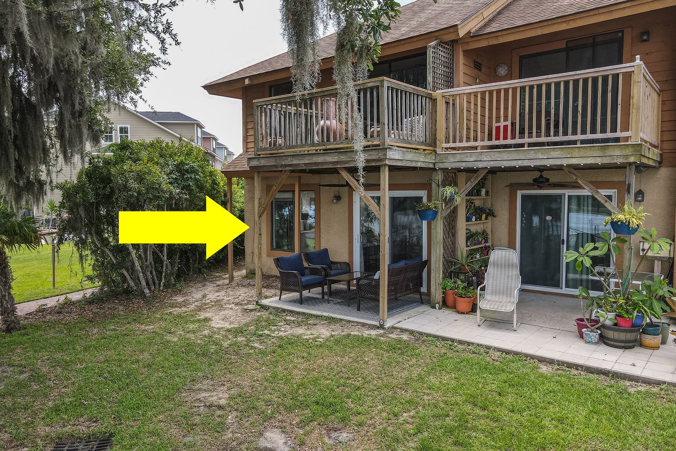 A two-story house with a balcony, outdoor seating, and potted plants.