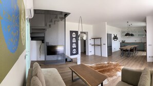 Ett modernt vardagsrum med en soffa, ett soffbord och en matta. En trappa leder upp till ett annat våningsplan.