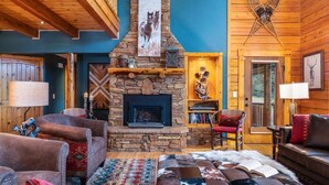 Una sala acogedora con chimenea de piedra, mobiliario de cuero y decoración rústica de madera.