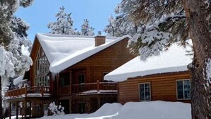 Una cabaña de madera con techo nevado y balcón.