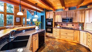 Una cocina amplia con armarios de madera, encimeras de granito y electrodomésticos modernos.