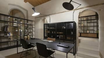 Una sala de reuniones moderna con una larga mesa, sillas negras y estanterías negras que exhiben libros y objetos decorativos.