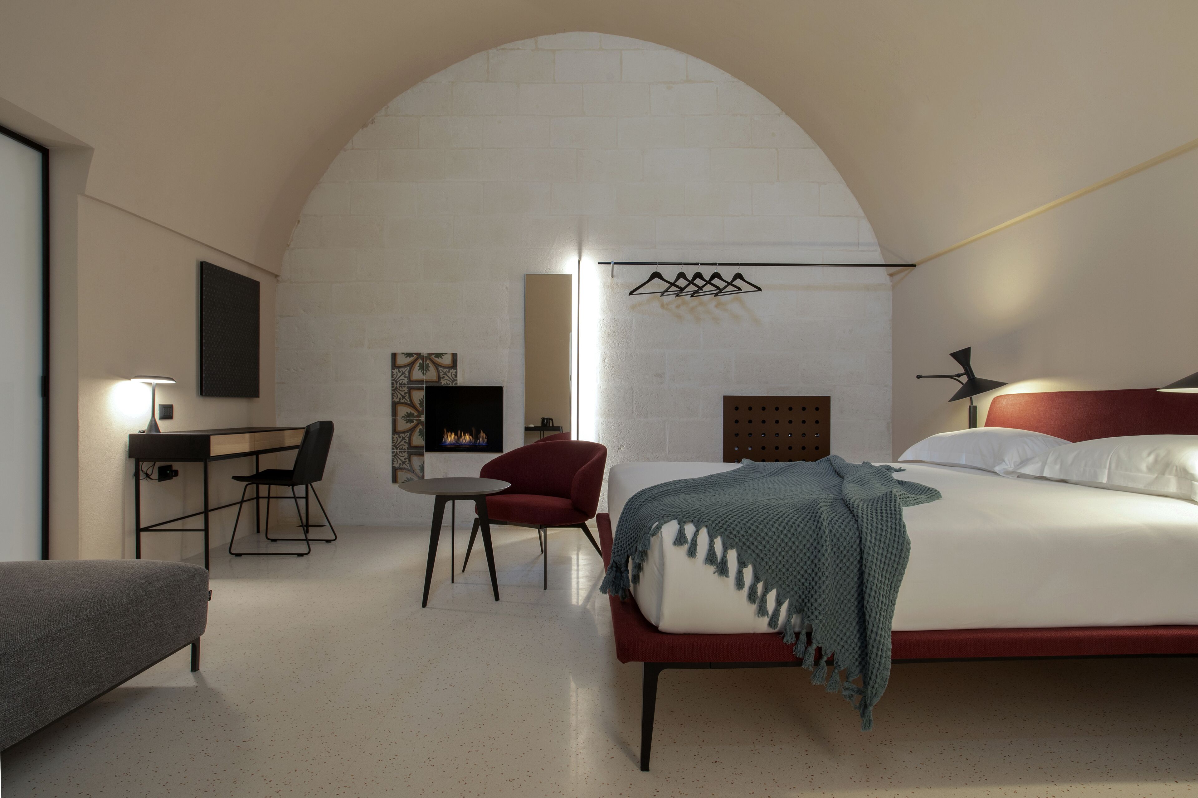 Una camera da letto moderna con un letto, una scrivania e una sedia, un camino e un soffitto a volta originale.