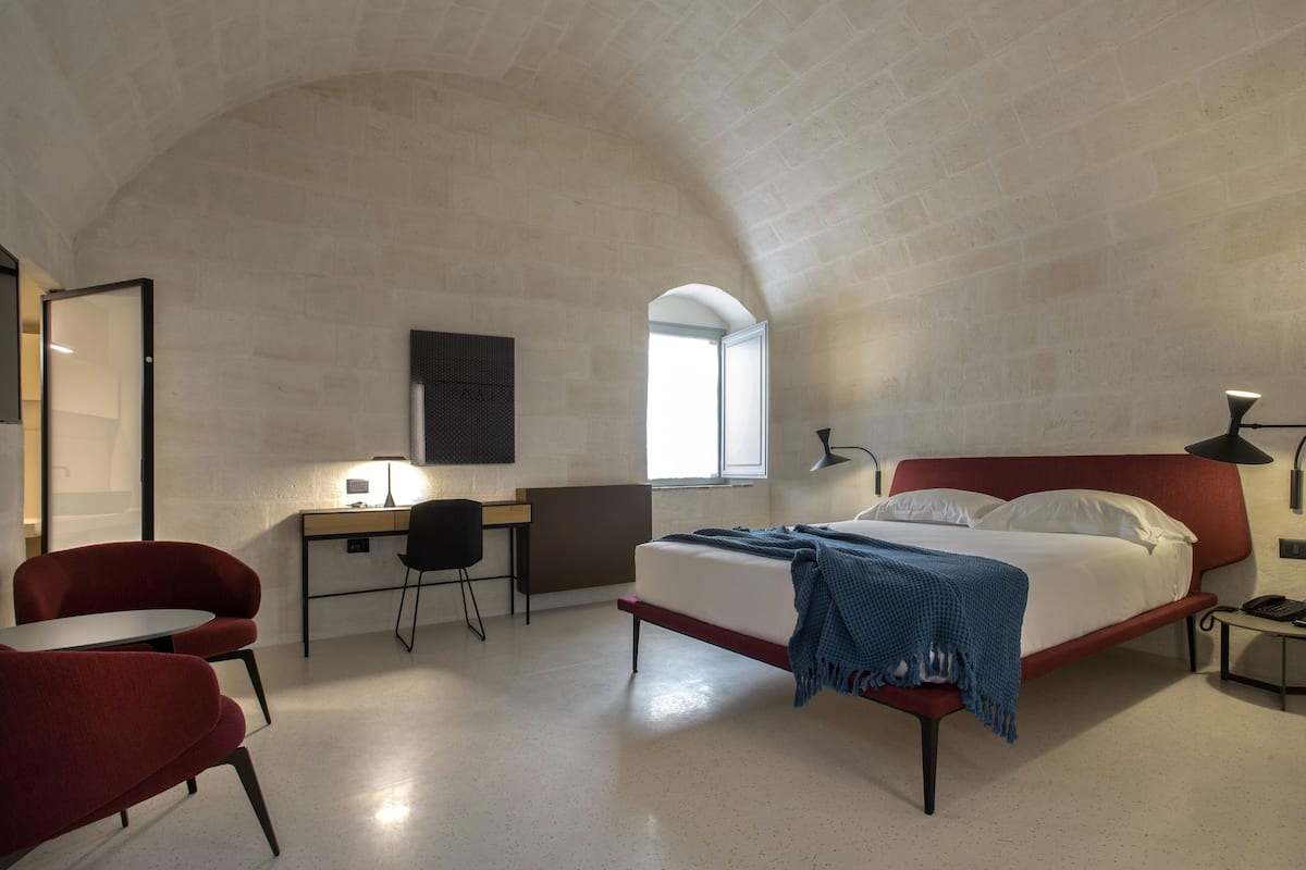 Ein modernes Schlafzimmer mit einem roten Bett, einem Schreibtisch und einem Sessel.