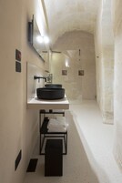 A modern bathroom with a round black sink, a mirror, and a towel rack.