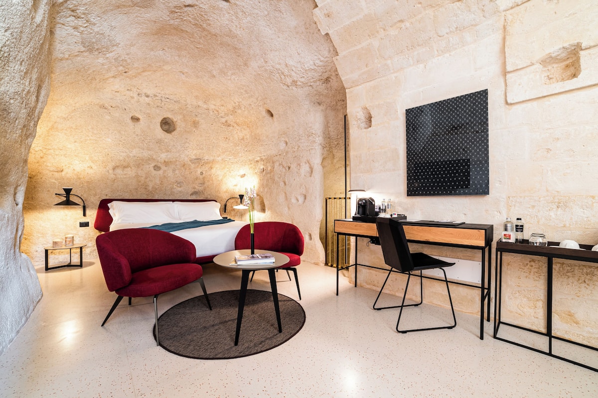 Ein gemütliches Hotelzimmer mit Bett, Schreibtisch, Stuhl und kleinem Tisch.