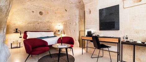 A cozy hotel room with a bed, a desk, a chair, and a small table.