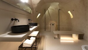Un baño moderno con un lavabo negro grande, un espejo y un banco.