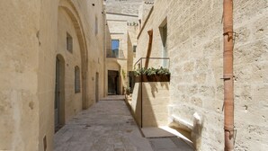 Un callejón estrecho con edificios de piedra, arcos y una viga de madera.