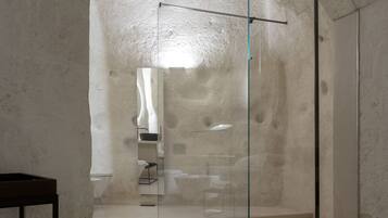 Un bagno moderno e minimalista con cabina doccia in vetro, zona lavabo a vista e un design semplice ed elegante.