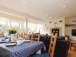 A dining area with a table set for breakfast, a fireplace, and a television in the living room.
