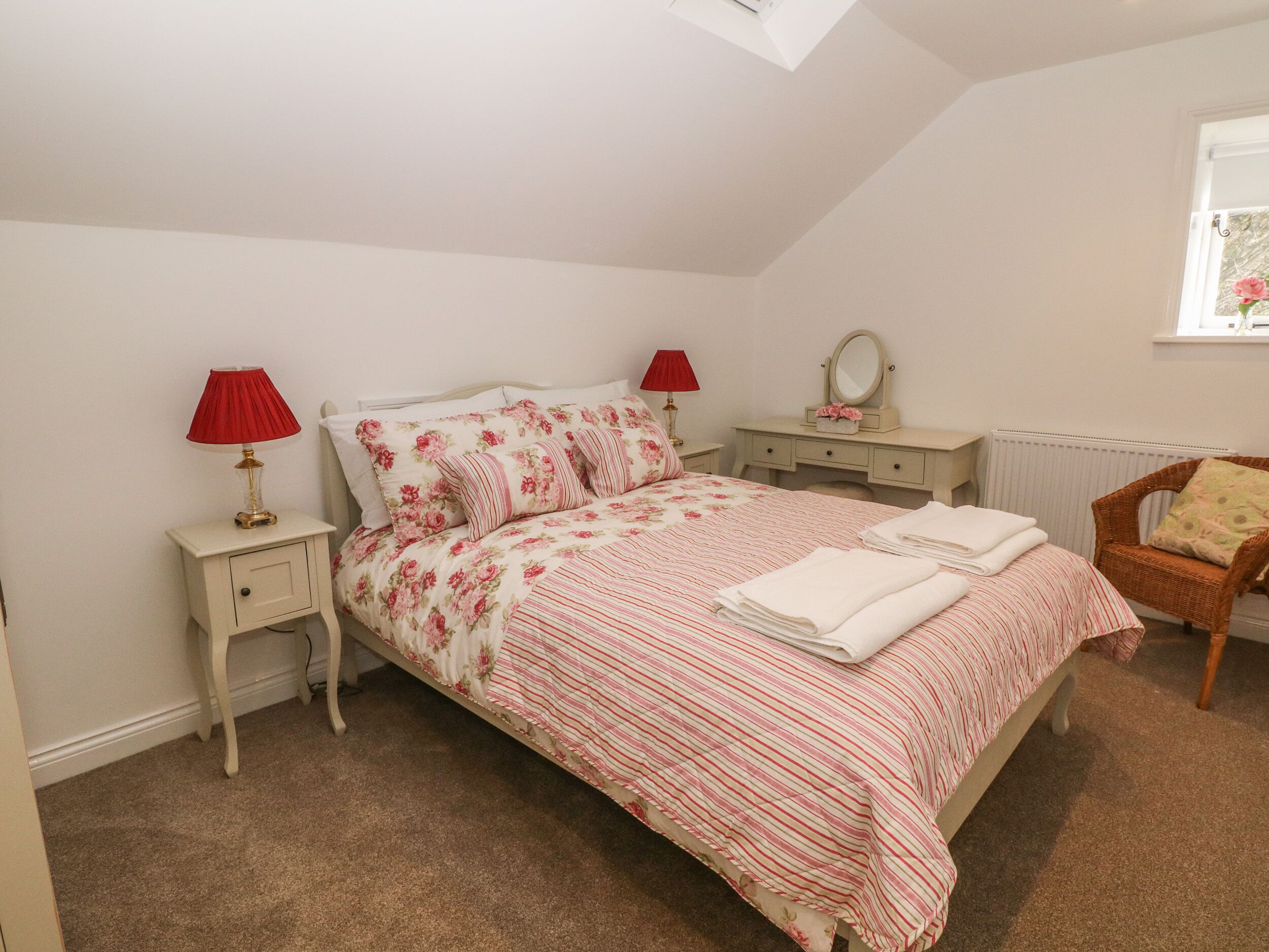 Une chambre à coucher comprenant un lit, deux tables de chevet, une commode, une chaise et une fenêtre.