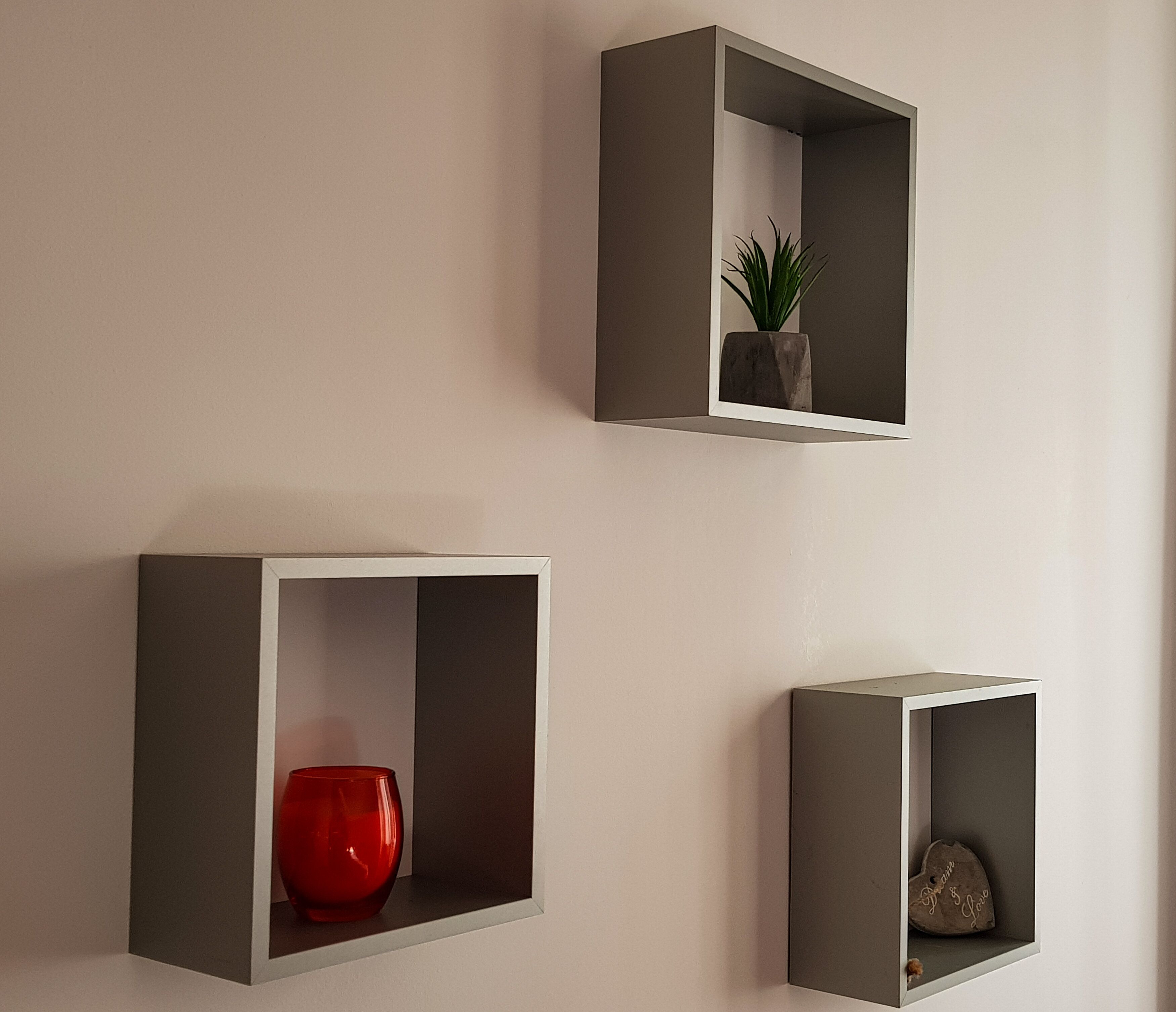Trois éléments de rangement à fixer au mur, chacun contenant des objets différents.