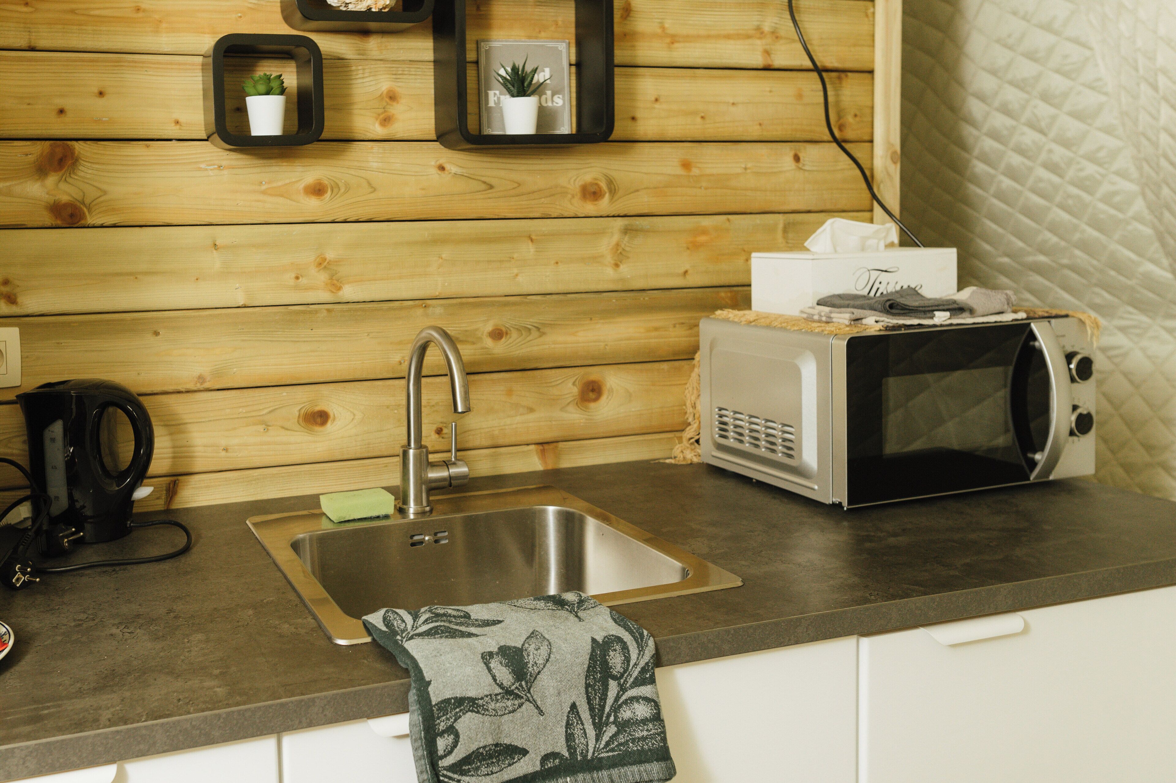 A kitchen with a stainless steel sink, a toaster, and a kettle.