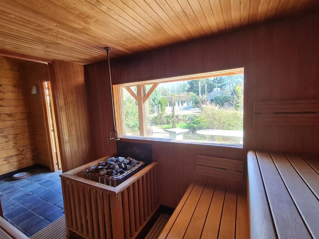 Une cabane en bois avec une cheminée en pierre, un banc et une fenêtre donnant sur un jardin.