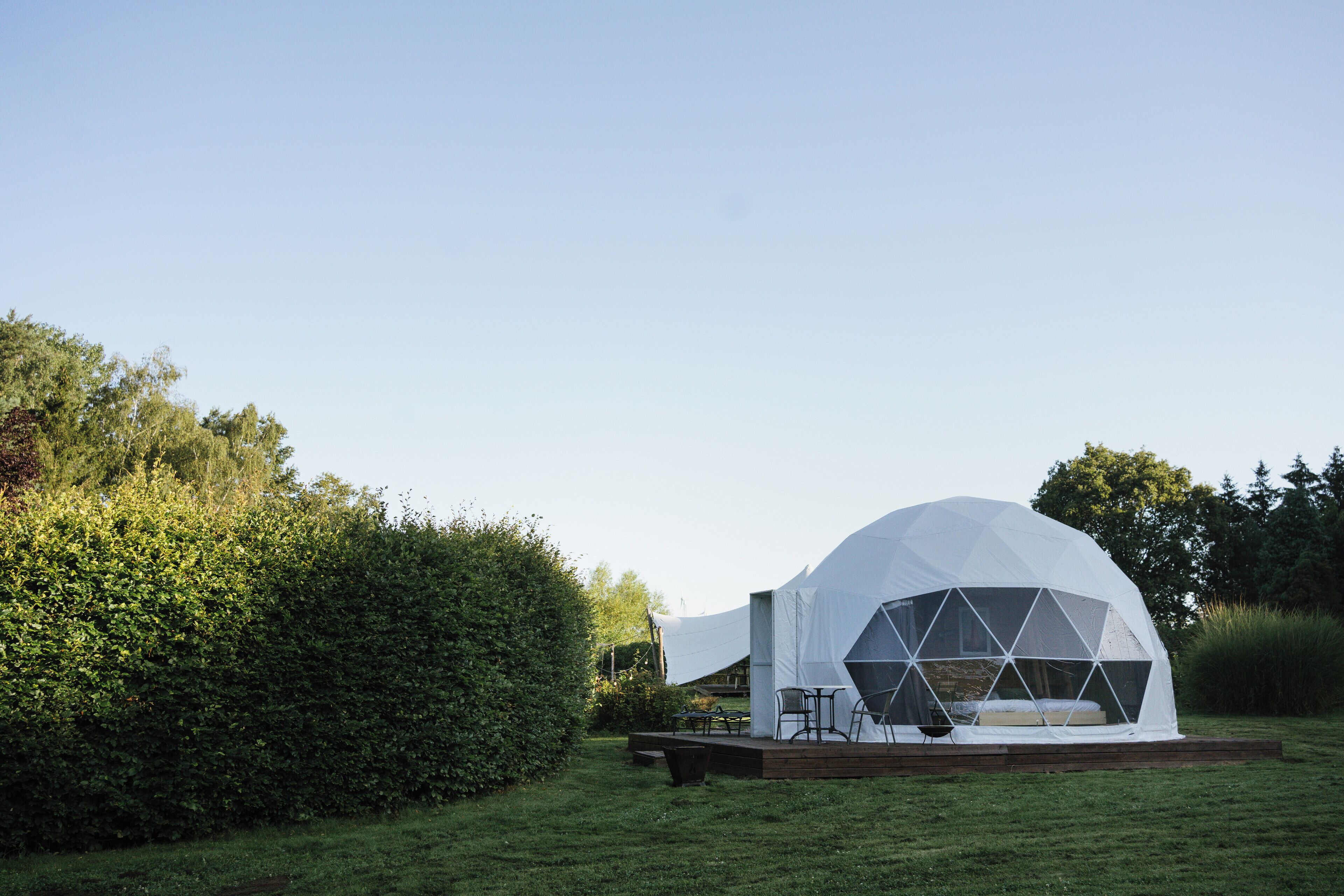 A geodesic dome tent with a wooden deck and seating area.