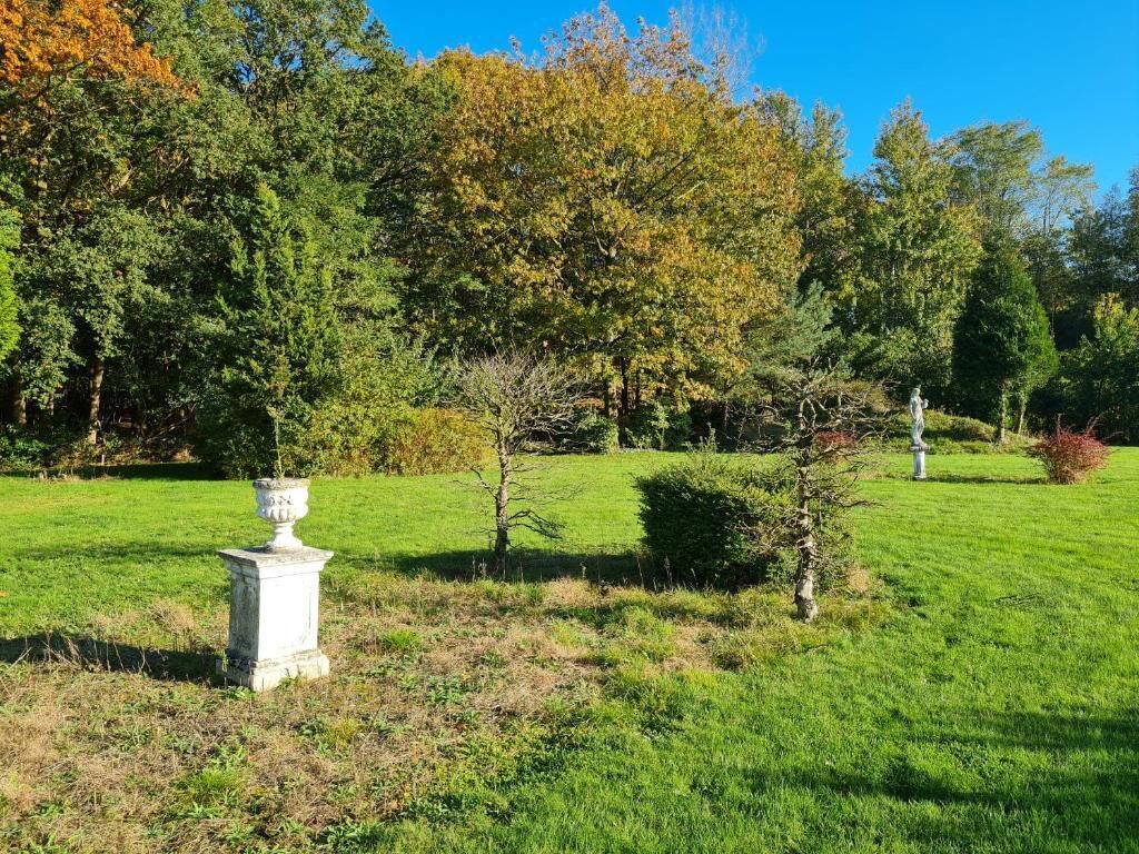 A well-maintained lawn with a white urn and a statue in the foreground, surrounded by trees and shrubs.