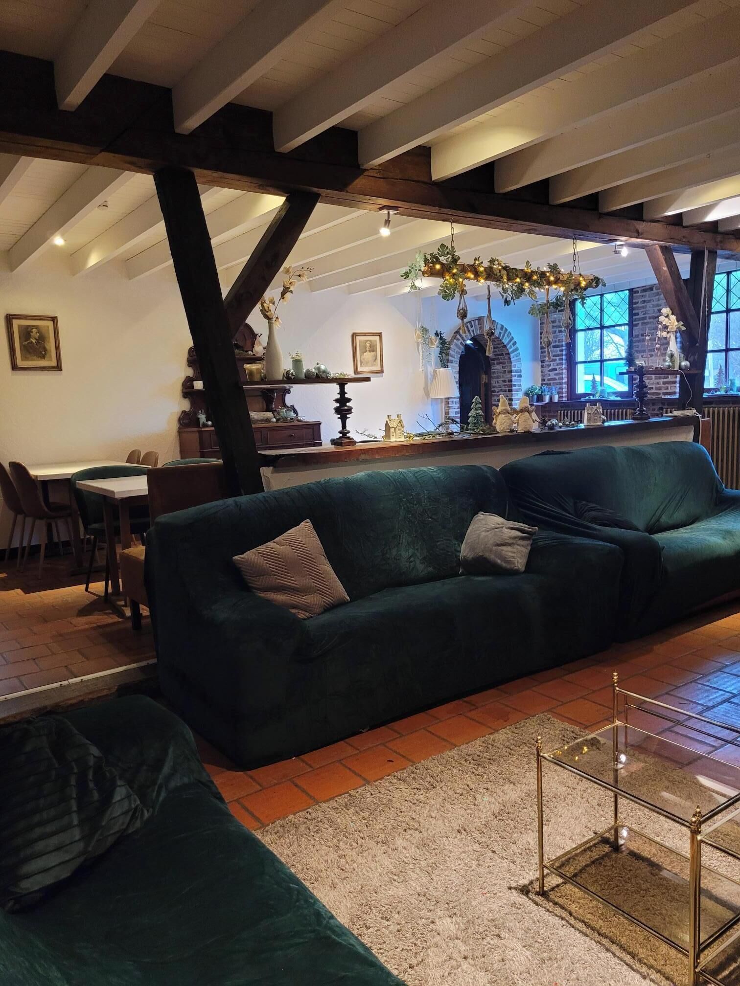 Ein gemütliches Wohnzimmer mit einem grünen Sofa, einem Essbereich mit Tisch und Stühlen sowie einer Küchenzeile mit einer Pendelleuchte.