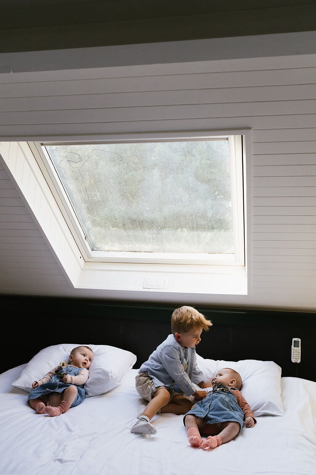 A room with a skylight, a bed, and a bedside table with a phone.