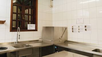 A kitchen with stainless steel countertops, a sink, and a window with a wooden frame.