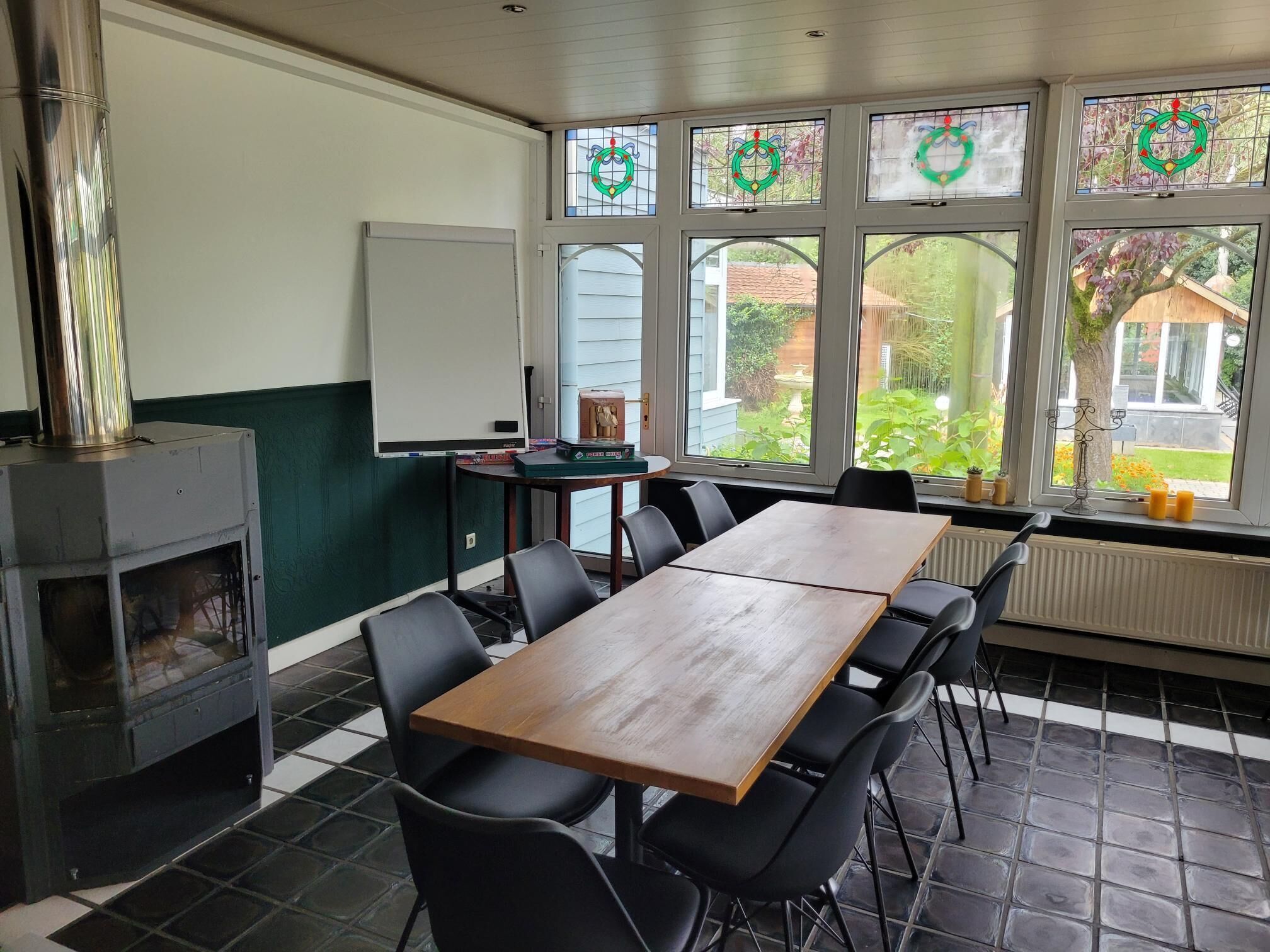 Una habitación con una larga mesa de madera, sillas negras, una pizarra y una chimenea.