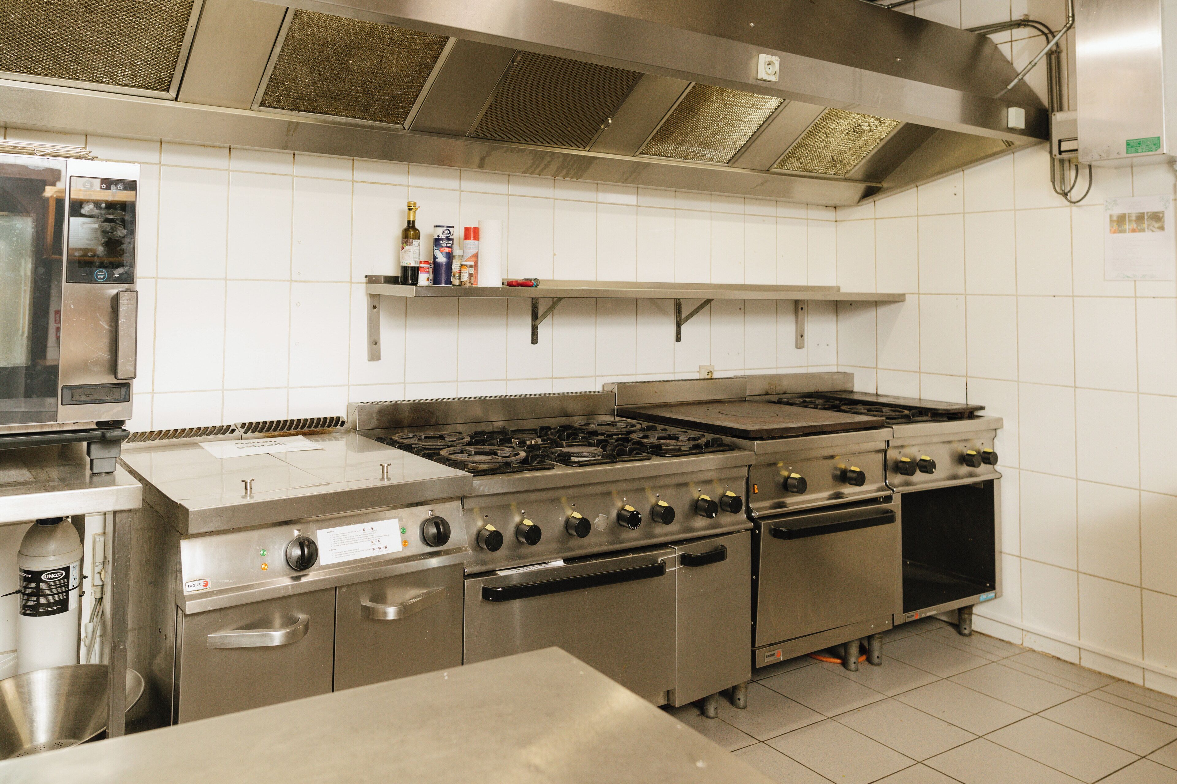Una cucina professionale dotata di elettrodomestici in acciaio inossidabile, tra cui un grande fornello e forno, e un forno a microonde.