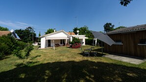 A house with a covered patio, a lawn, and a wooden fence.